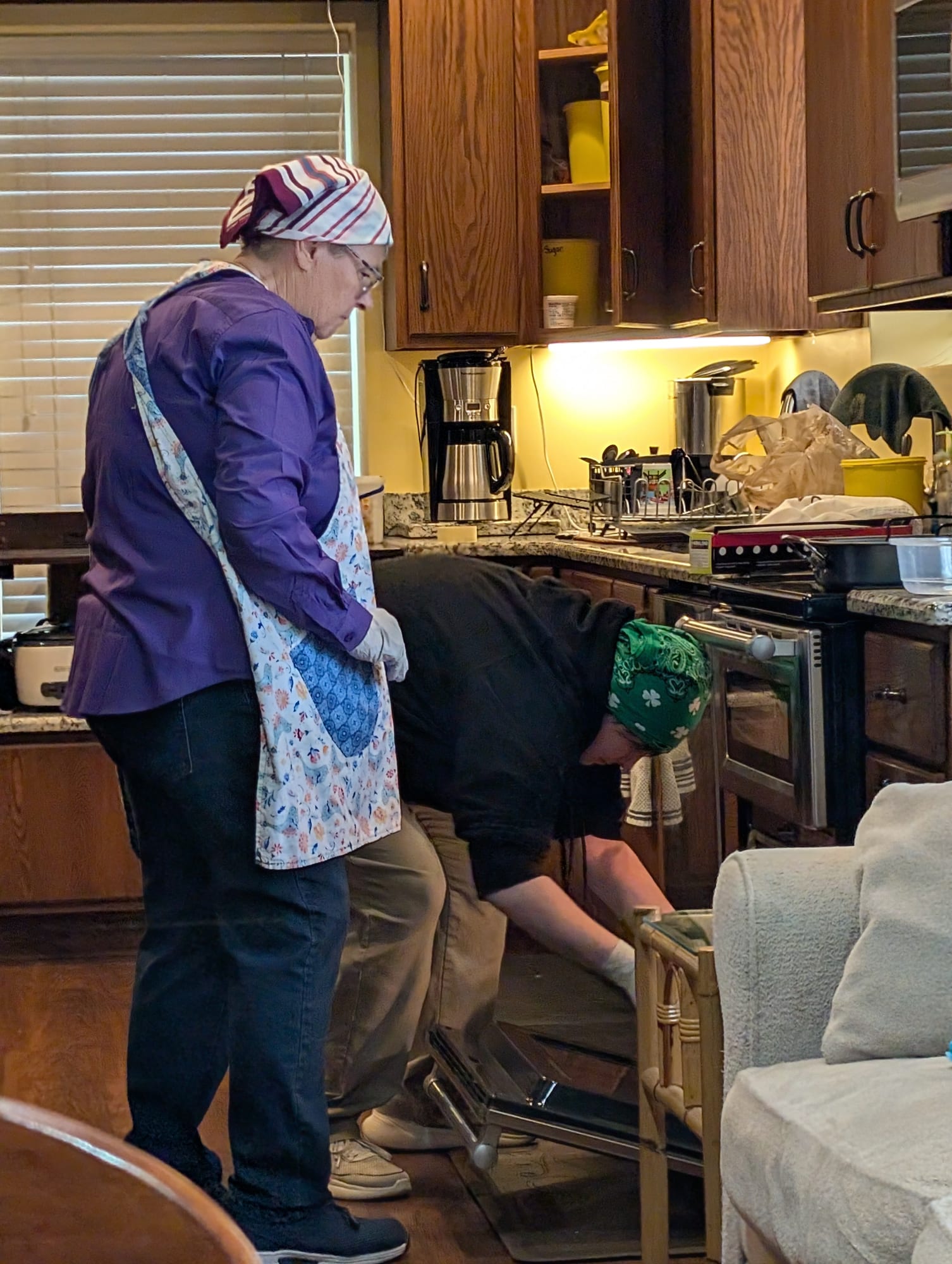 Two women at the oven, cooking together.