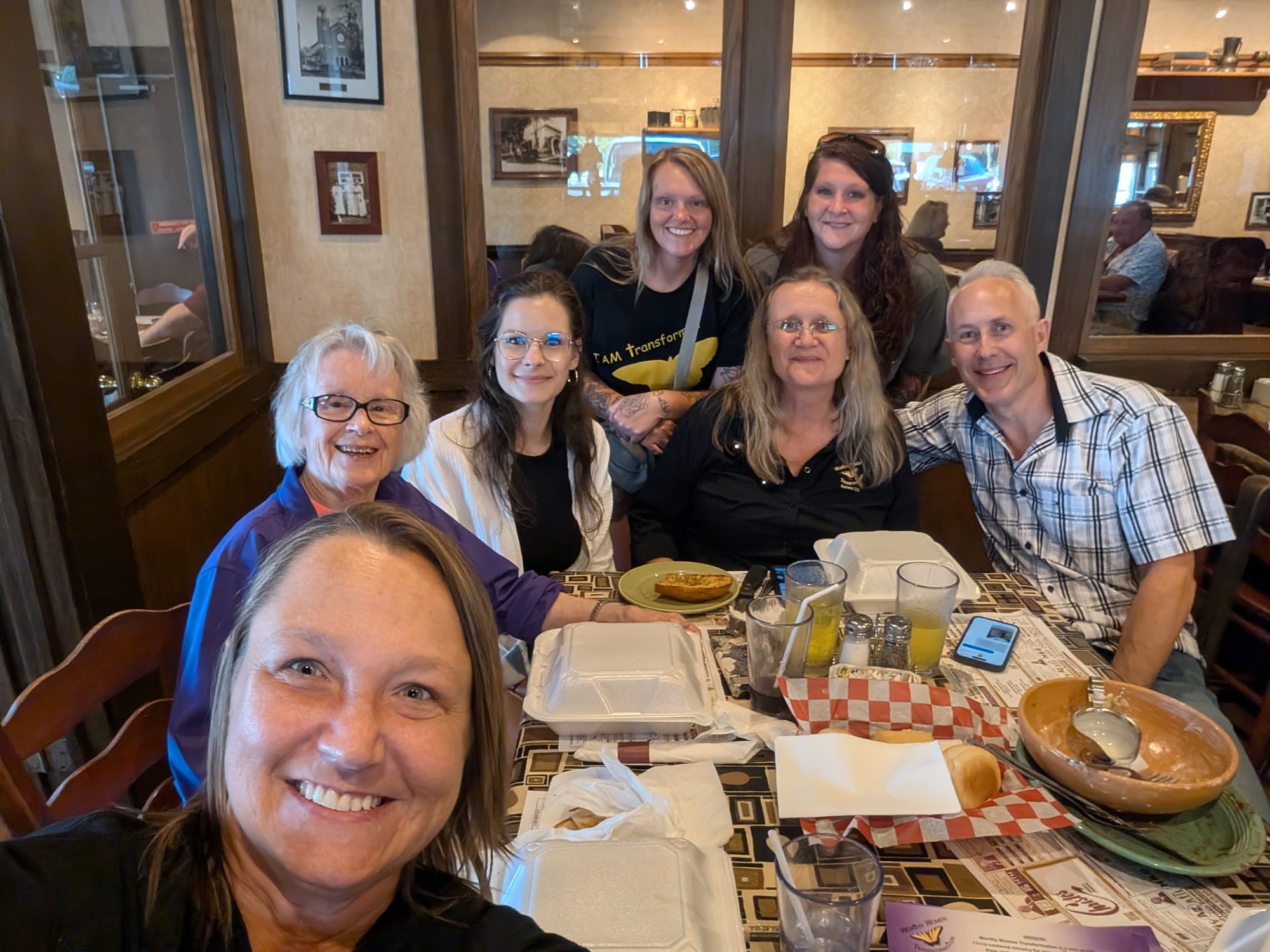 The Worthy Women crew around a restaurant table.
